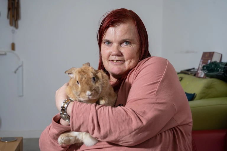 Supported customer Julie, cuddling her pet rabbit
