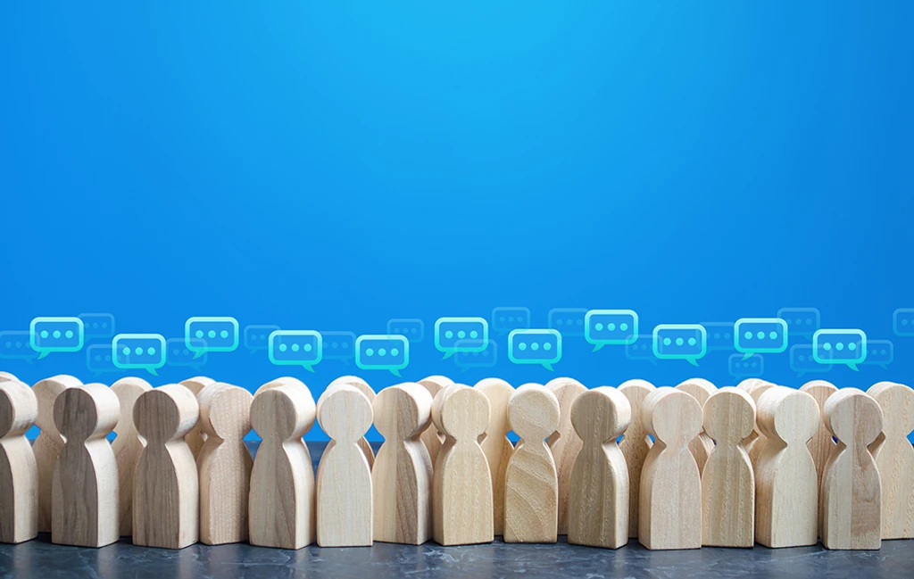 Wooden figures of people with speech bubbles above their heads