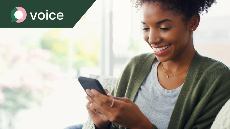 A woman looking at a mobile phone in her hand and smiling