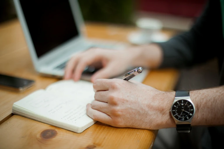 Hands with a laptop and writing note book