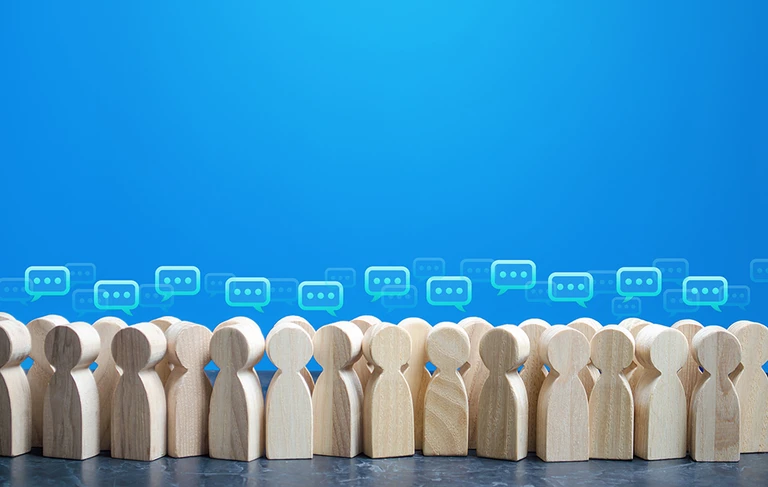 Wooden figures of people with speech bubbles above their heads