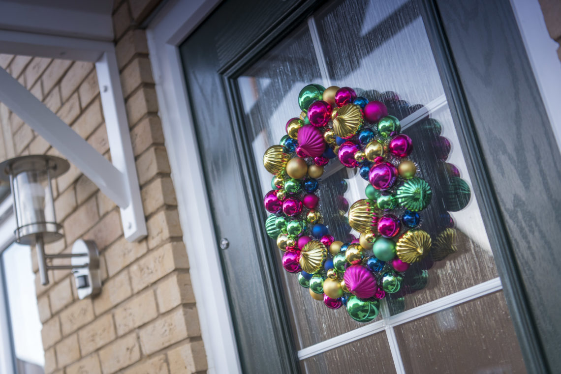Wreath of colourful Christmas baubles hanging on a front door