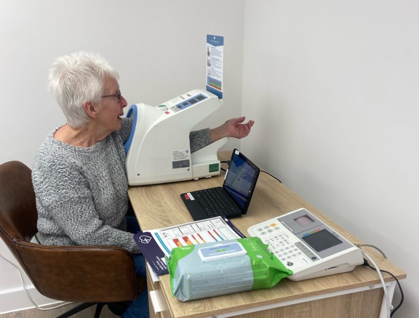 Lady sat at a table with her arm in a blood pressure machine