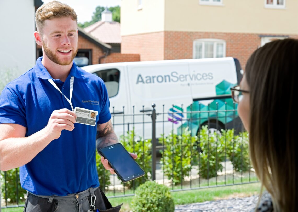 An employee of Aaron Services showing his ID badge to someone at a door