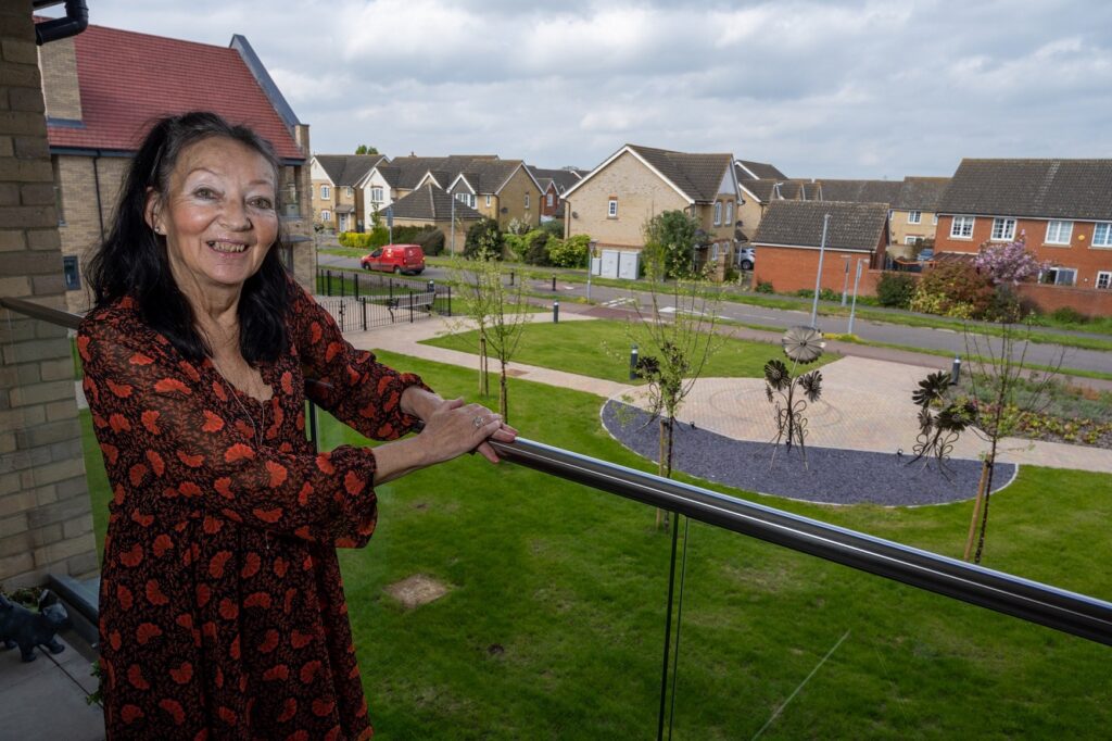 Jacky standing on her balcony overlooking landscaped gardens