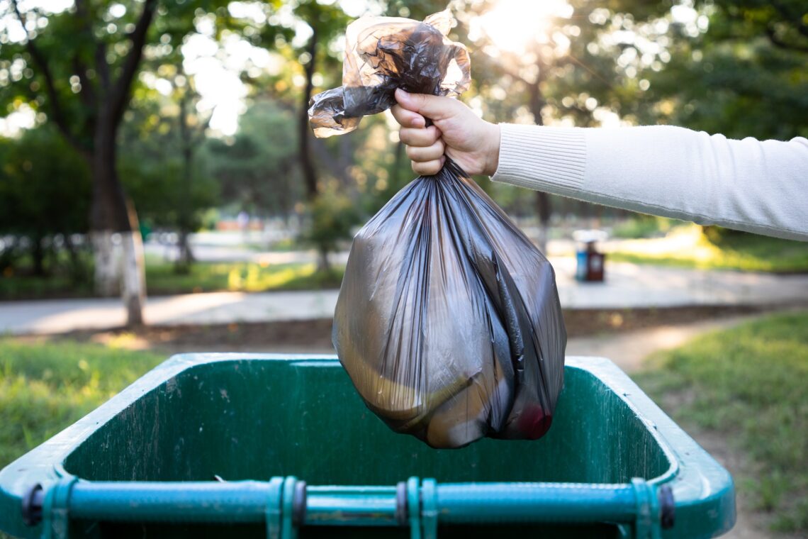 A person placing rubbish in a bin