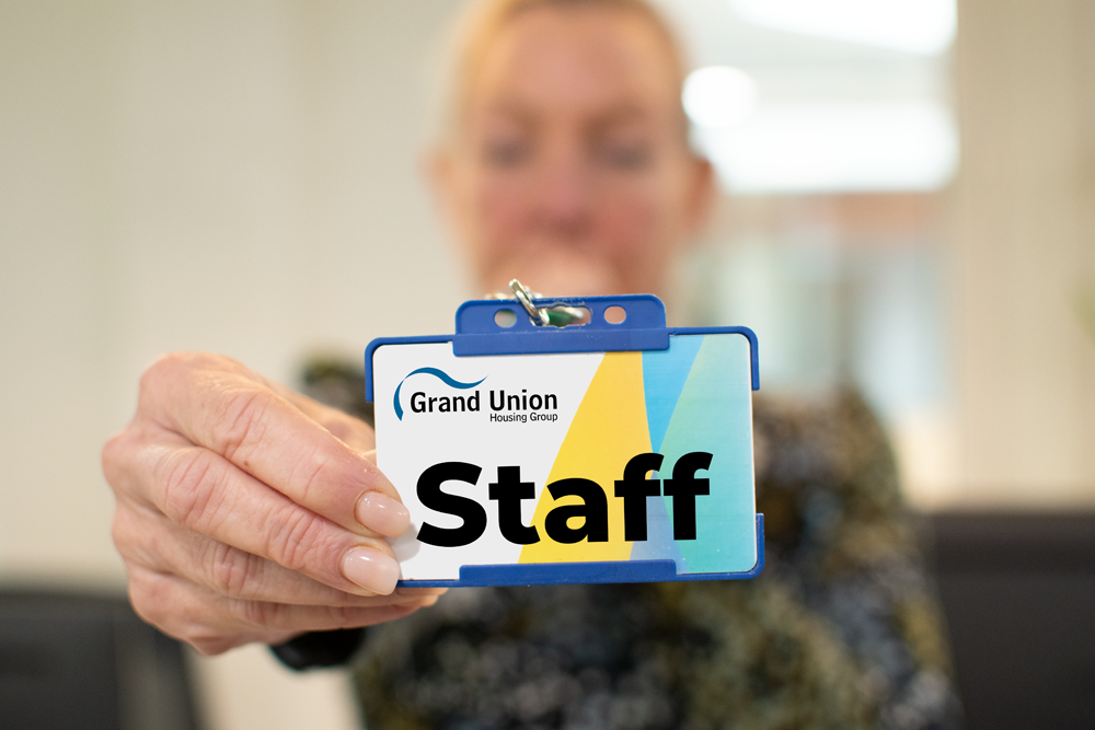 Female Grand Union colleague holding a badge saying "staff"