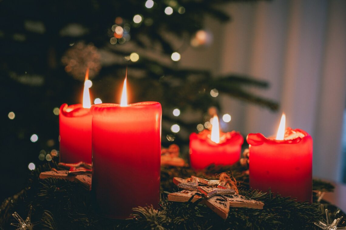 Four red candles in front of a Christmas tree